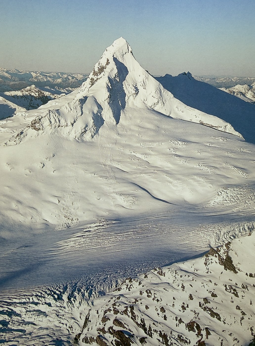 A snowy pyramid-shaped alpine peak above a glacier